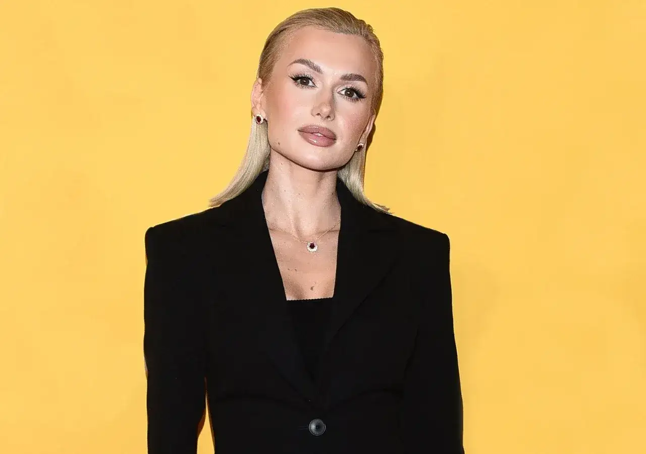 Młoda influencerka w czarnym żakiecie, która stoi za sukcesem najmłodszej polskiej milionerki z internetu, pozuje na żółtym tle.