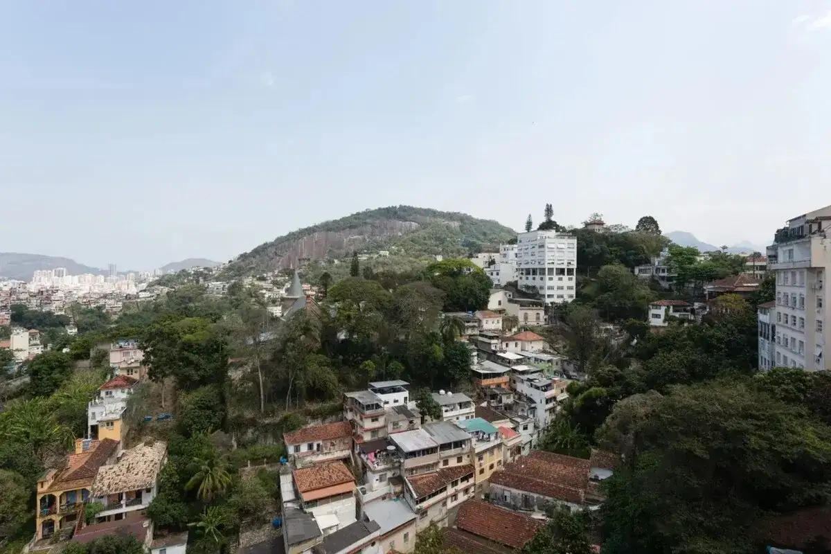 Bunte Häuser schmiegen sich an grüne Hügel in Santa Teresa, Rio. Ein Blick über die Stadt mit dem markanten Berg im Hintergrund.