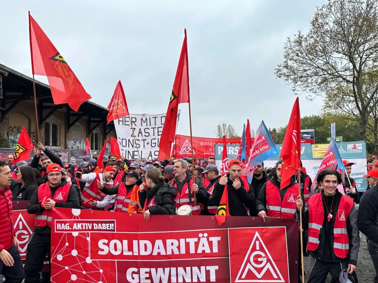 IG Metall Mitglieder demonstrieren mit roten Fahnen und Spruchb&auml;ndern f&uuml;r Solidarit&auml;t.