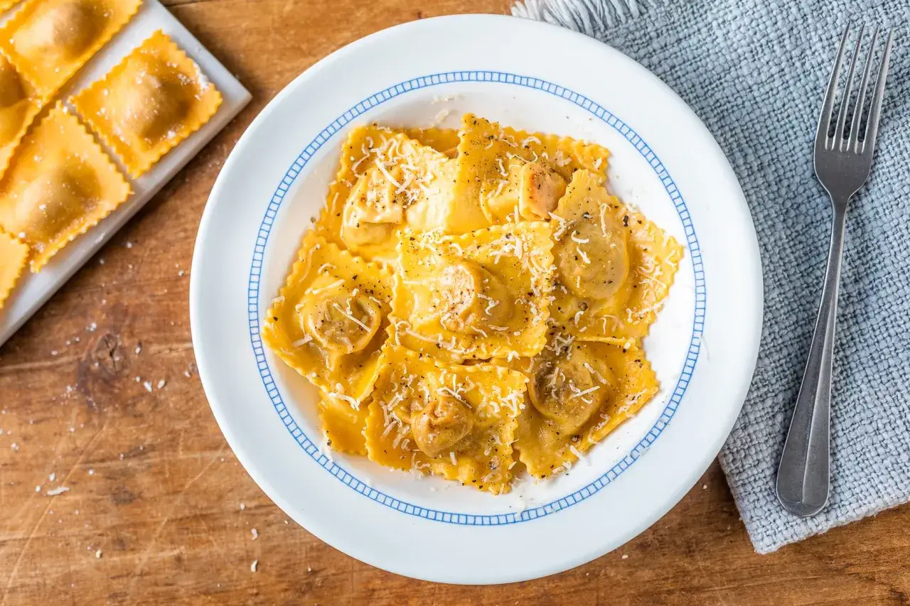 Tortelli di zucca appena preparati, conditi con parmigiano e pepe nero, pronti per essere gustati.