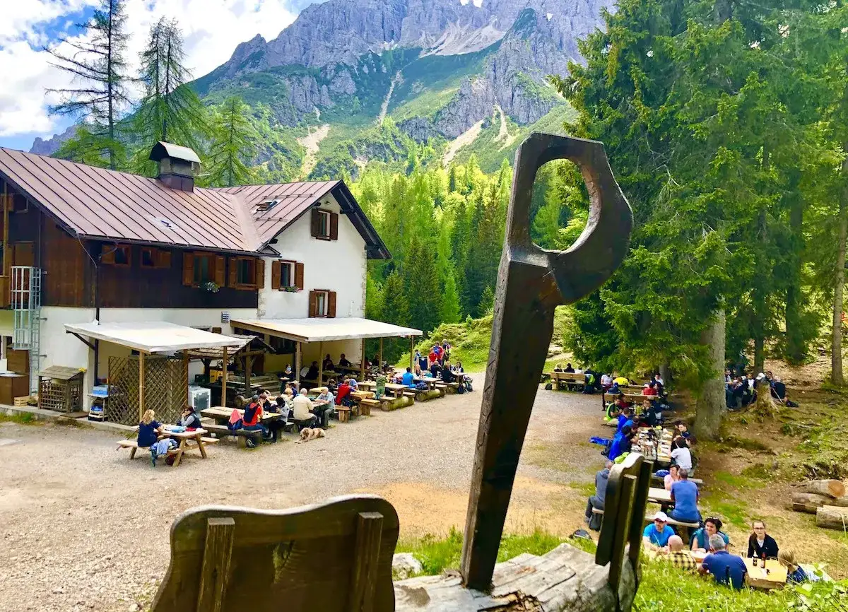 Il rifugio Giaf, immerso nel verde, accoglie escursionisti a tavola con vista sulle maestose montagne.