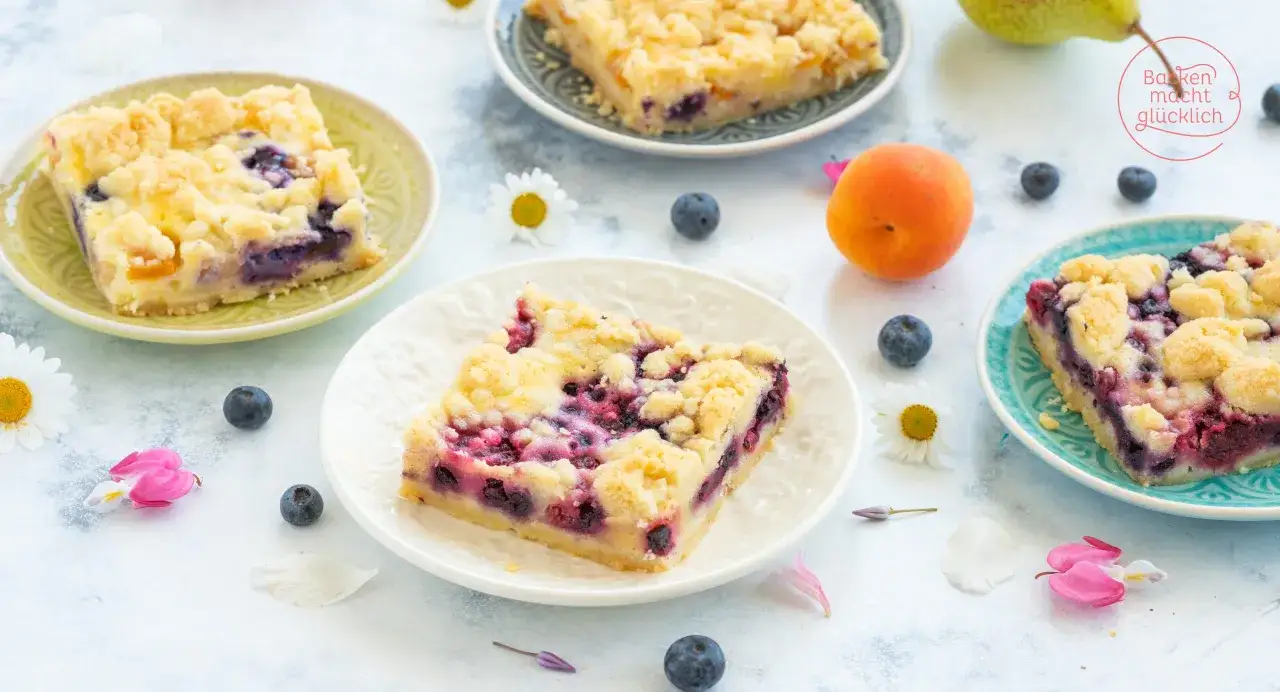 Saftige Blechkuchen Rezepte mit Blaubeeren und Streuseln, garniert mit frischen Früchten und Blumen.