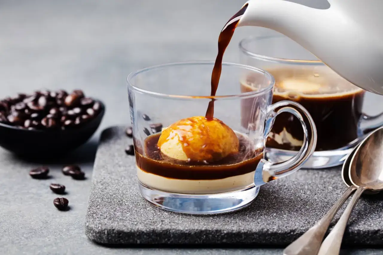 Ein hei&szlig;er Espresso flie&szlig;t &uuml;ber eine Kugel Vanilleeis in einem Glas. Ein k&ouml;stlicher Affogato al caff&egrave;, bereit zum Genie&szlig;en.