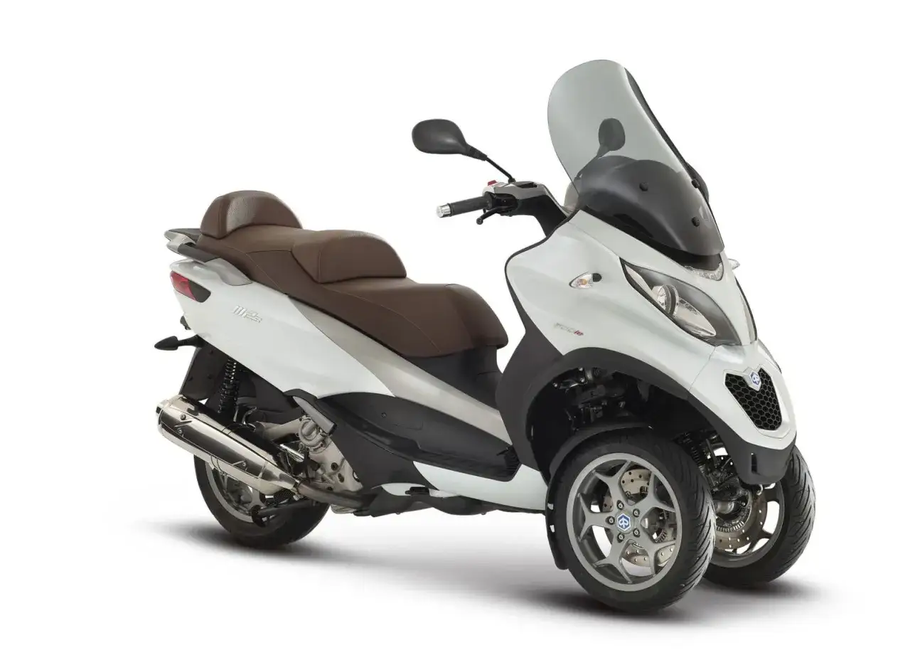 Scooter blanco de tres ruedas con asiento marrón. Recuerda que las motos de tres ruedas necesitan carnet de moto.