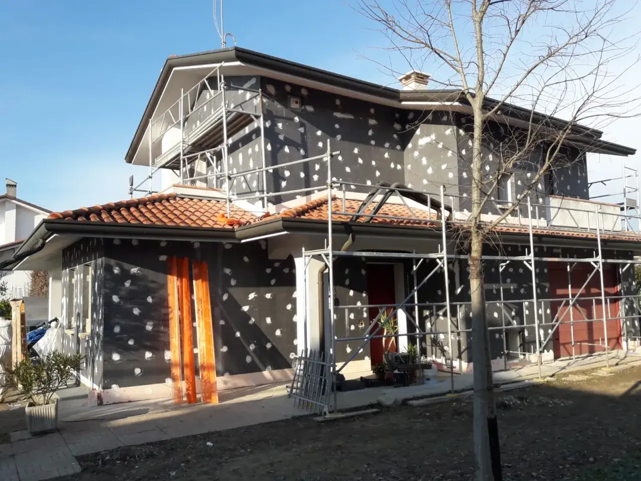 Casa in ristrutturazione con cappotto termico in materiale EPS. L'edificio &egrave; circondato da ponteggi.