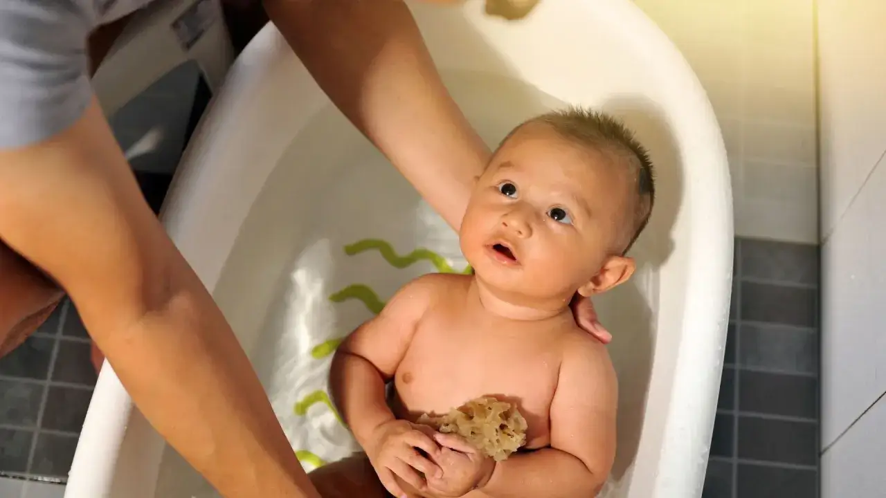 Bebé en bañera, asegurando la temperatura del agua para un baño seguro y divertido.