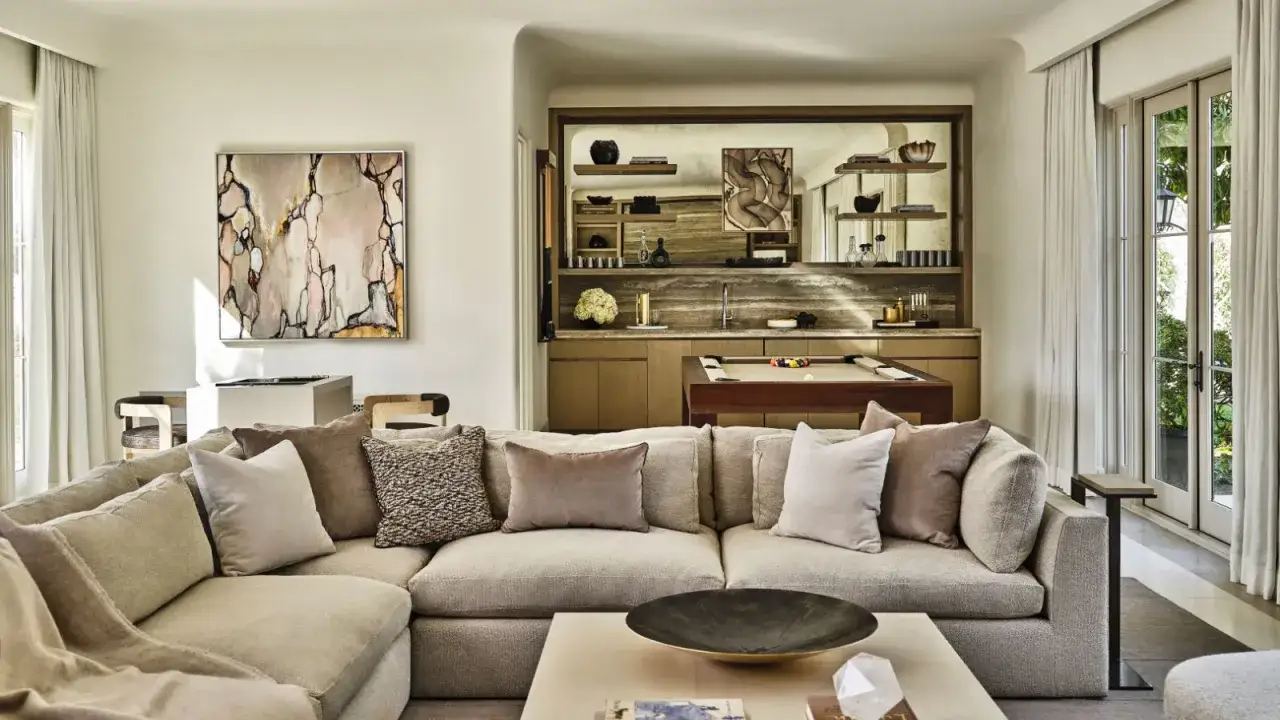 Ein beiges Ecksofa mit vielen Kissen, das zeigt, welche Sofa Farbe ist modern. Im Hintergrund ein Billardtisch und eine Bar.