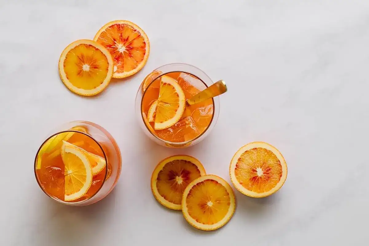 Orzeźwiający drink z amaretto i wódką, ozdobiony plasterkami pomarańczy. Idealny na letnie popołudnie.
