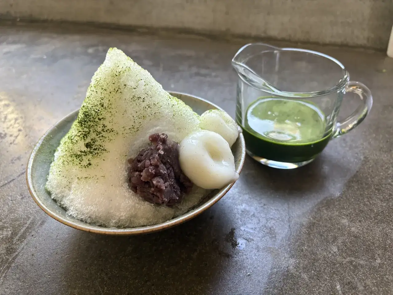 Japońskie lody z zieloną herbatą matcha, fasolą adzuki i mochi. Obok dzbanuszek z syropem matcha.