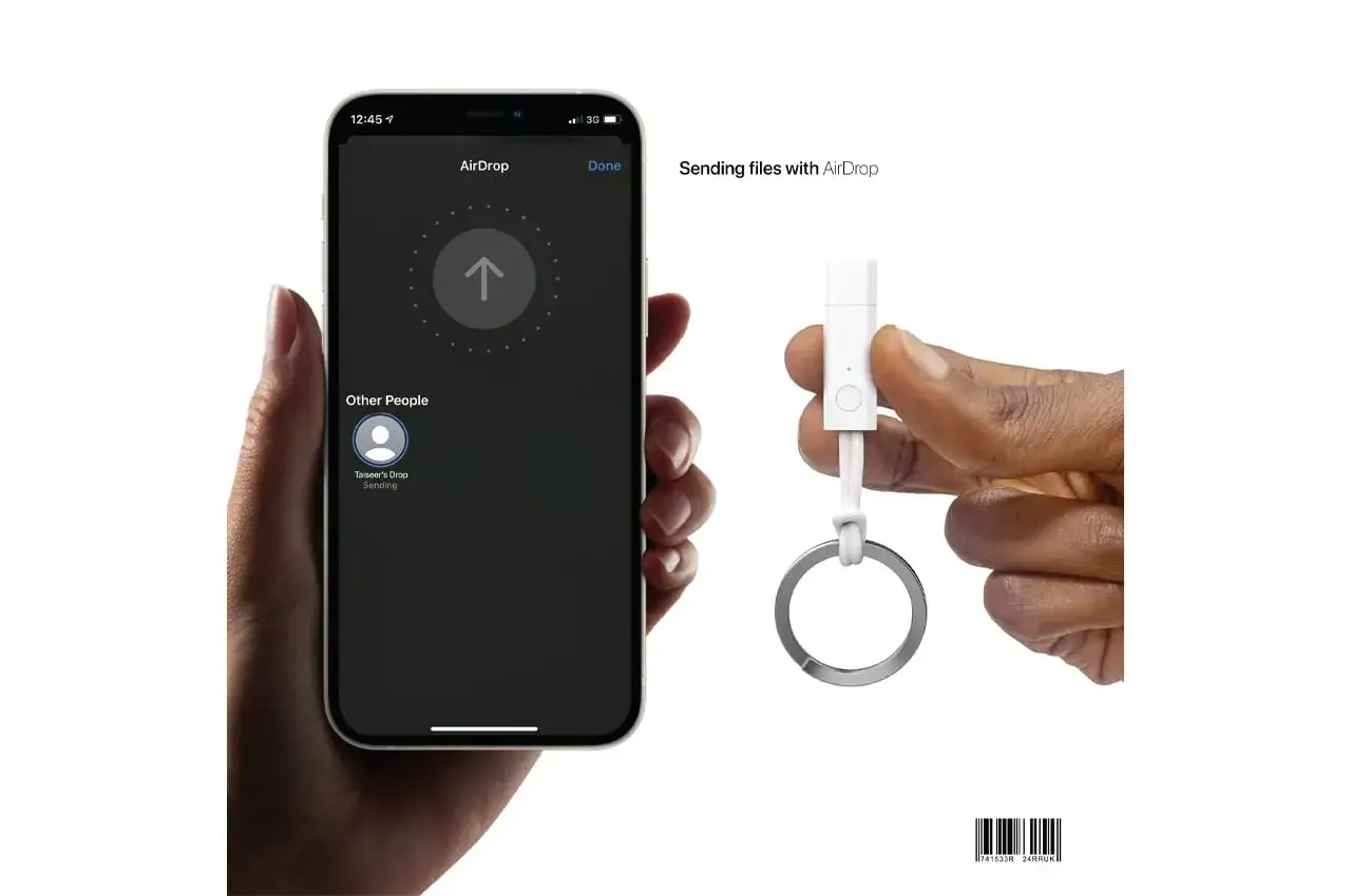 Dłoń trzyma iPhone'a z aktywnym AirDrop, pokazującym wysyłanie plików. Obok, inna dłoń trzyma brelok z adapterem USB-C. Dowiedz się, airdrop co to jest i jak działa.