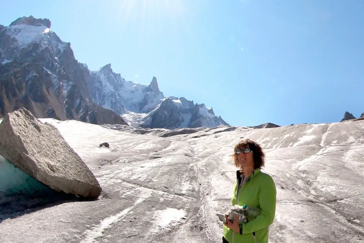 Catherine Destivelle, en compagnie d'un compagnon imaginaire, sourit face à un paysage de haute montagne enneigée.