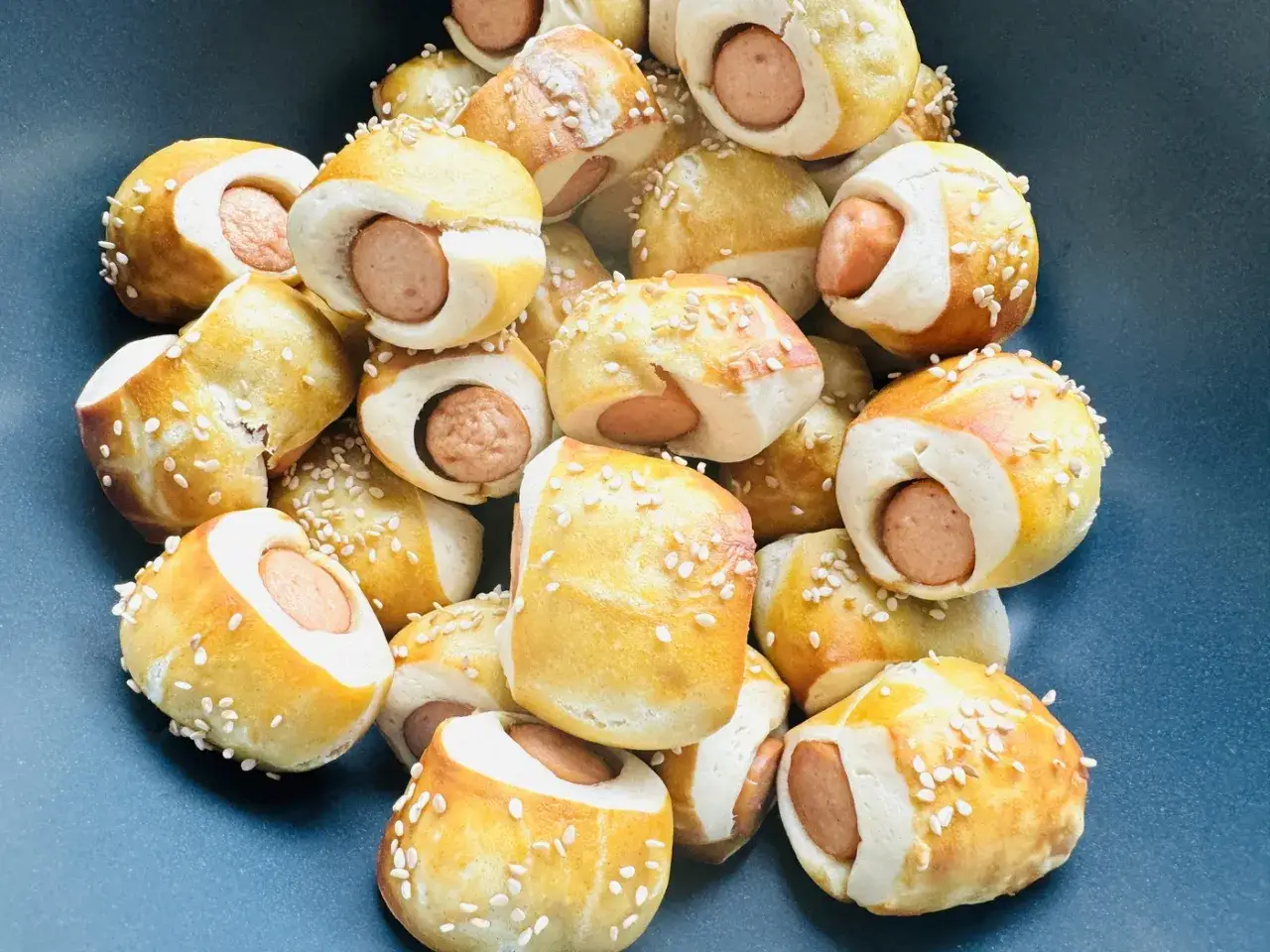 Herzhaftes Fingerfood für Kinder: Kleine Würstchen im Teigmantel, bestreut mit Sesam. Perfekt als kalter Snack.