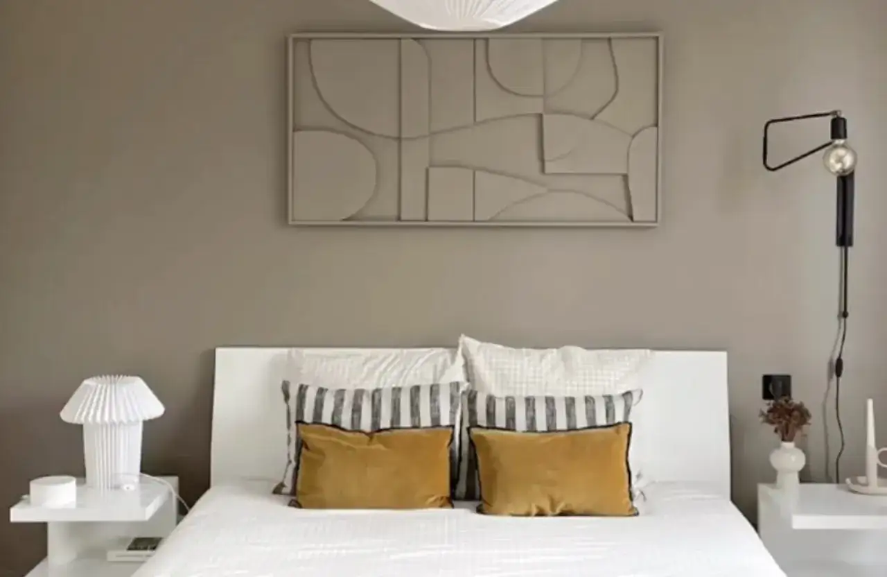 Un tableau en relief à faire soi-même, aux formes abstraites et douces, décore le mur au-dessus d'un lit confortable.