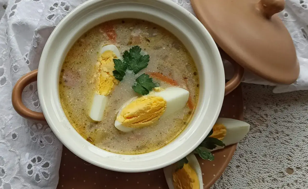 Aromaticzny żurek z jajkiem i majerankiem, podany w białej miseczce, czeka na spróbowanie.