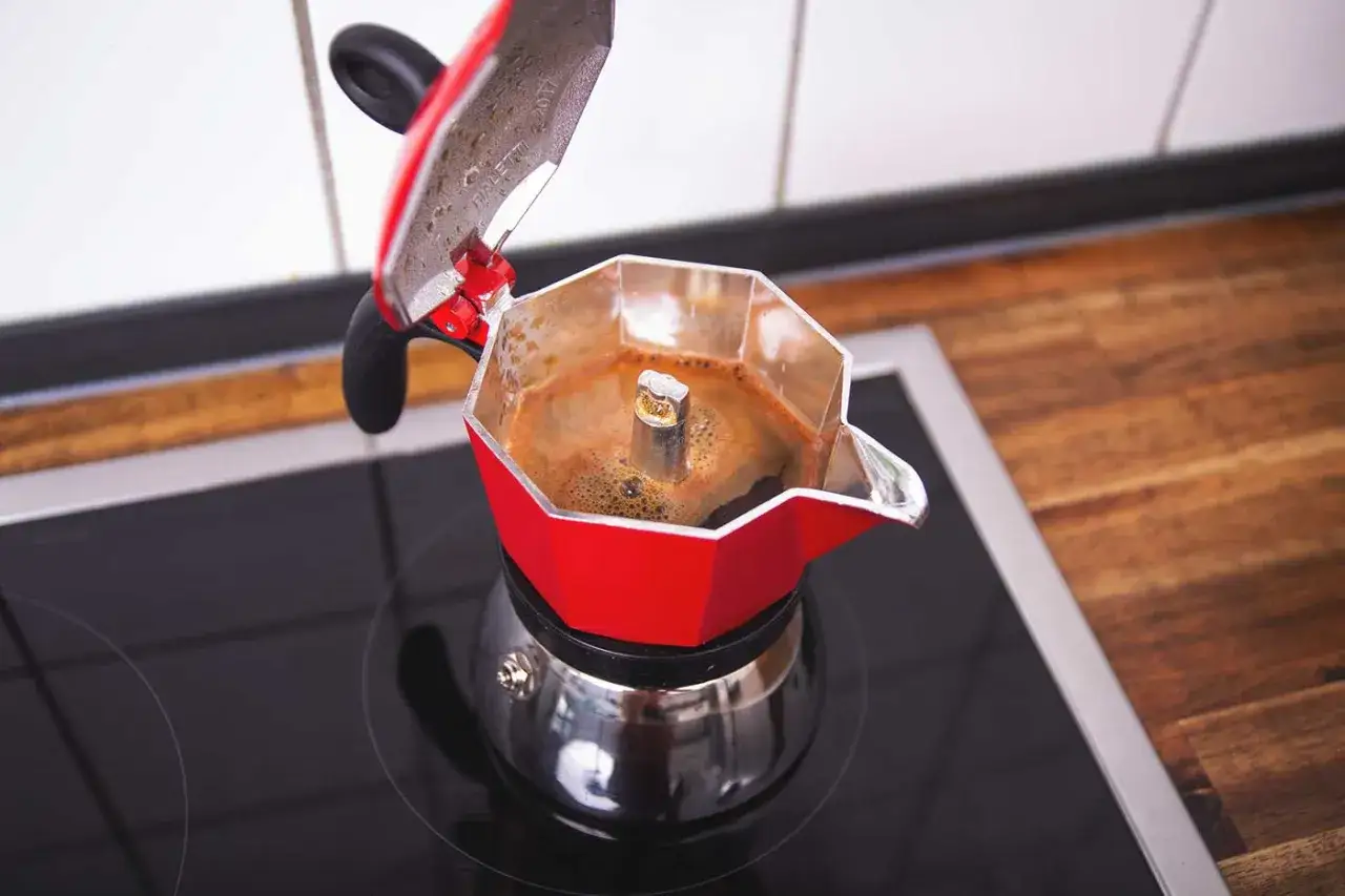 Rote Bialetti Kaffeekanne auf dem Herd, die k&ouml;stlichen Kaffee f&uuml;r die Zubereitung br&uuml;ht.