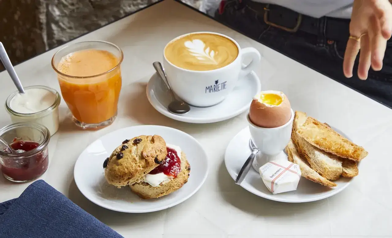 Un &oelig;uf &agrave; la coque, un scone &agrave; la confiture, du jus d'orange et un caf&eacute; latte pour un brunch parfait.
