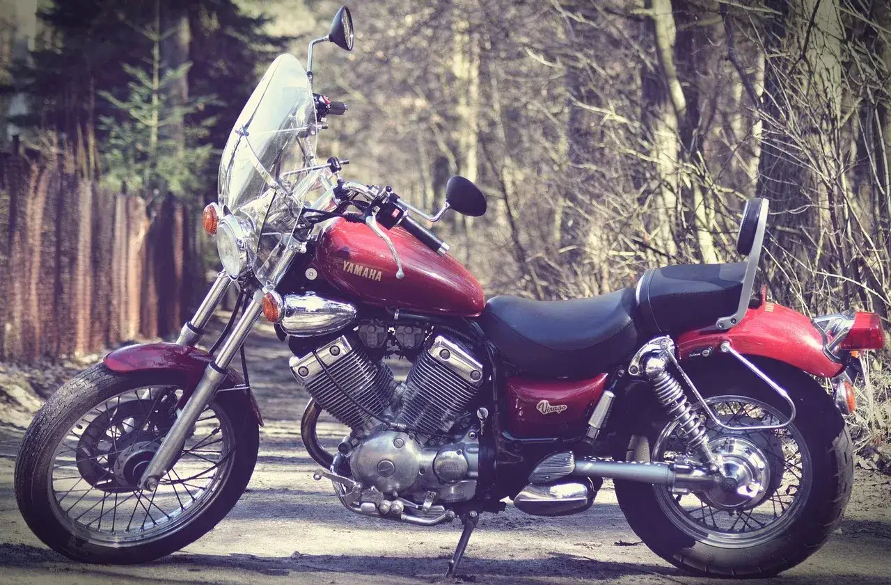Czerwony motocykl Yamaha Virago, jeden z klasycznych motocykli, zaparkowany na leśnej drodze.