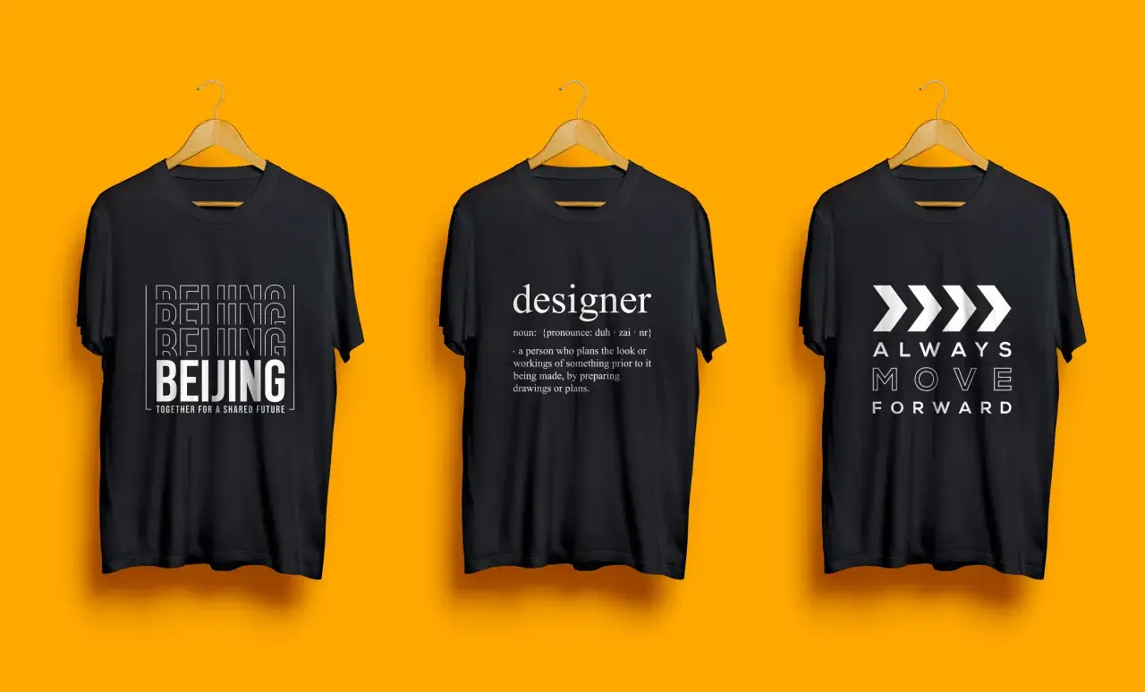 Trois t-shirts noirs suspendus. L'un affiche 