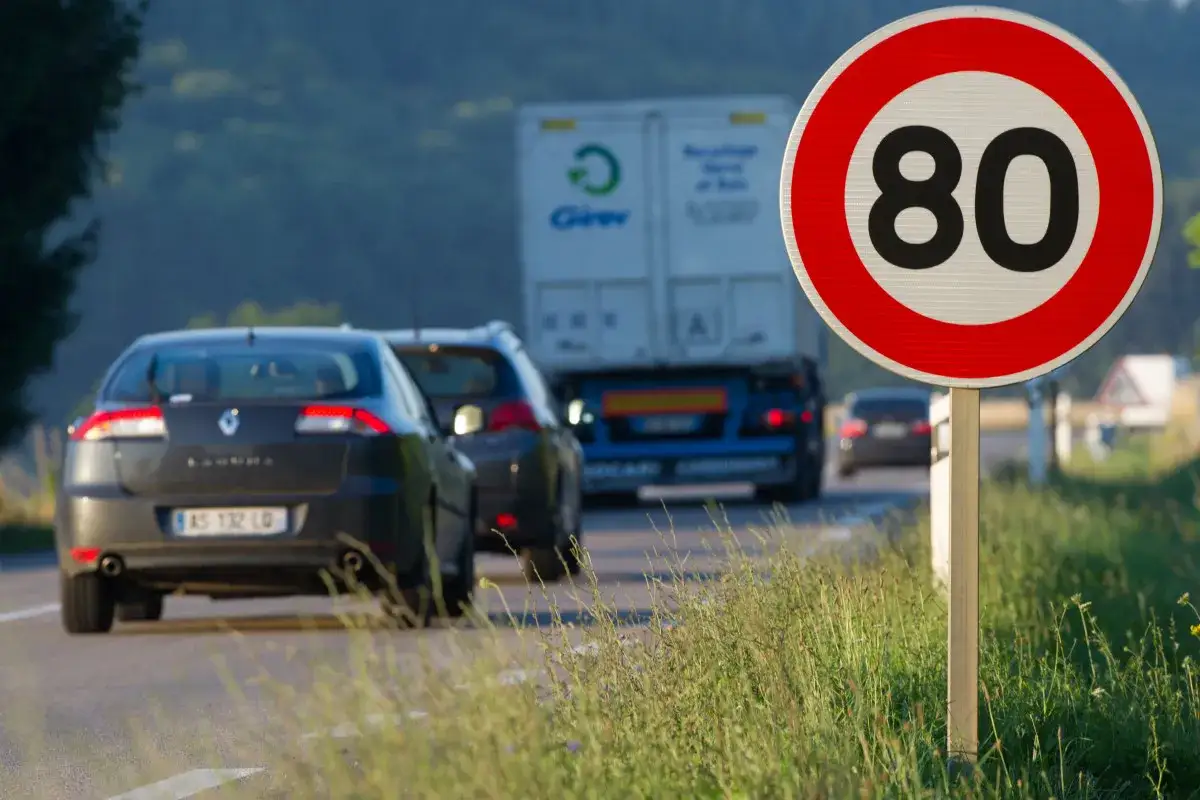 Panneau de limitation de vitesse &agrave; 80 km/h, rappelant la vitesse maximale autoris&eacute;e sur cette route o&ugrave; circulent plusieurs voitures et un camion.
