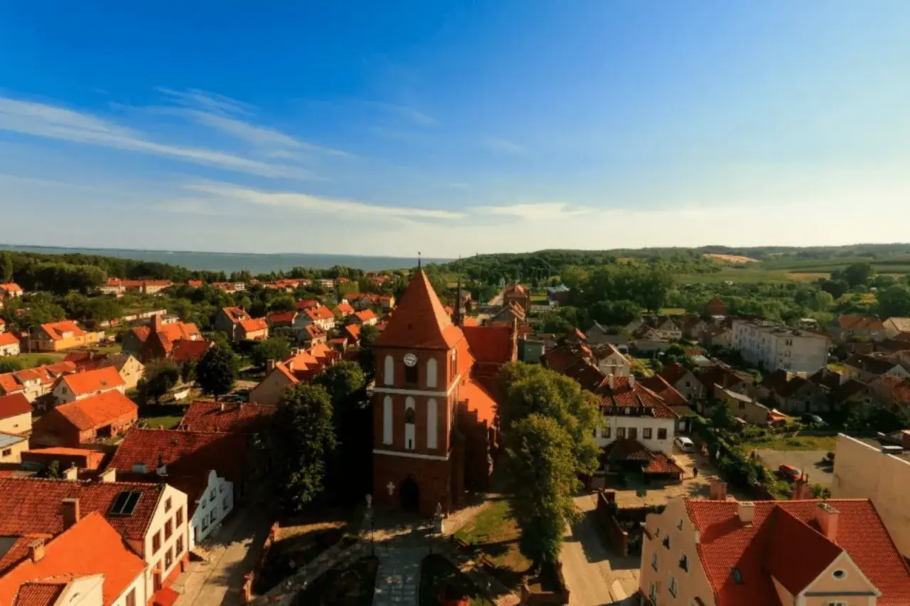 Widok na miasto z kościołem i czerwonymi dachami. Tolkmicko atrakcje zachęcają do zwiedzania urokliwych zakątków.