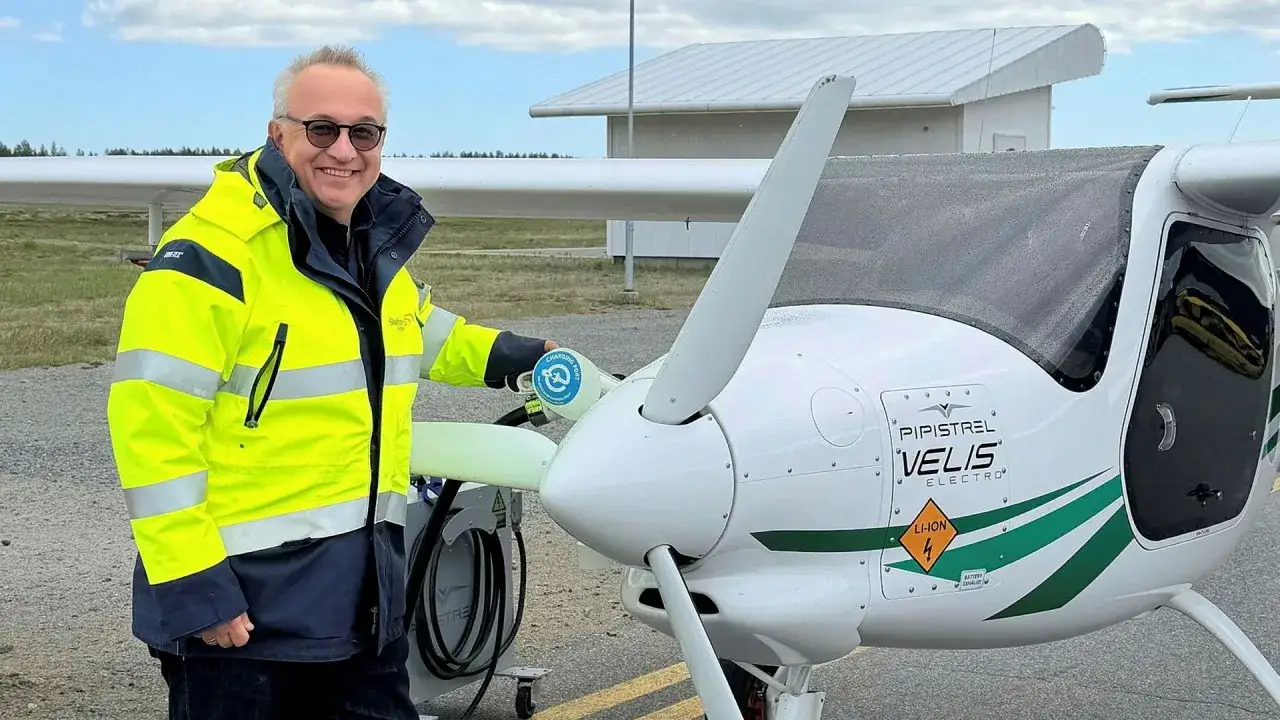 Man i gul jacka laddar elflygplan vid en green flight academy.