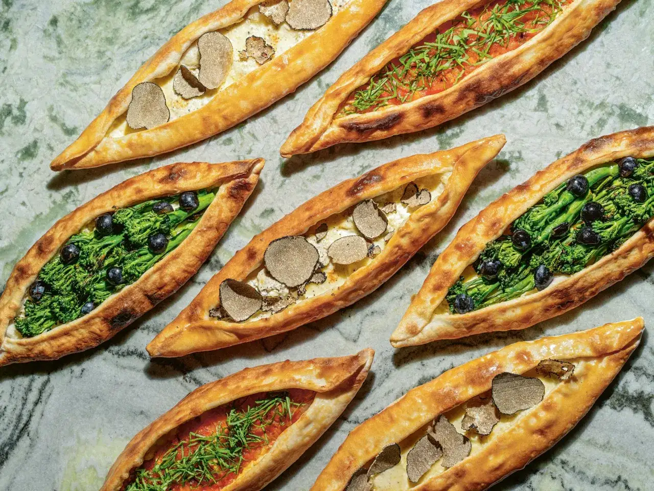 Verschiedene Pide-Varianten: mit Tr&uuml;ffeln, Brokkoli und Oliven, oder Tomaten und Kr&auml;utern. Was ist Pide? Ein t&uuml;rkisches Fladenbrot.
