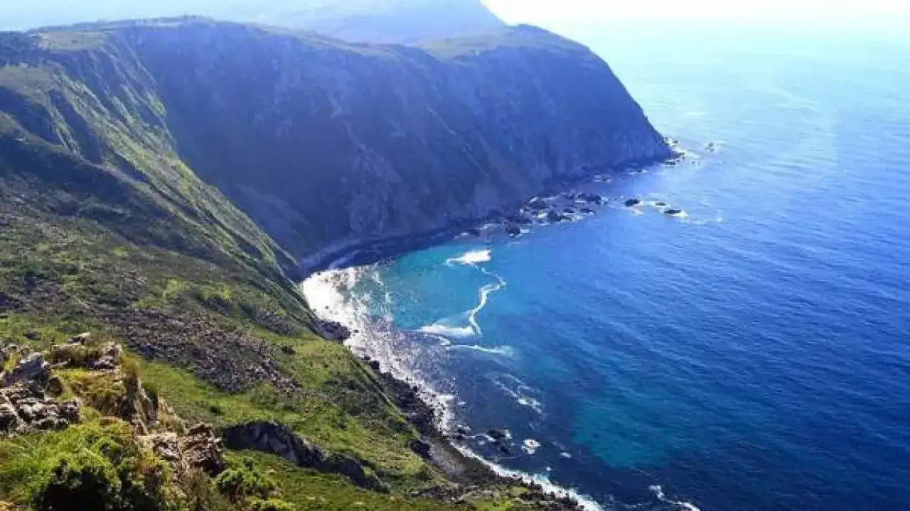 Acantilados verdes y rocosos se unen al mar azul cerca de la garita de Herbeira.