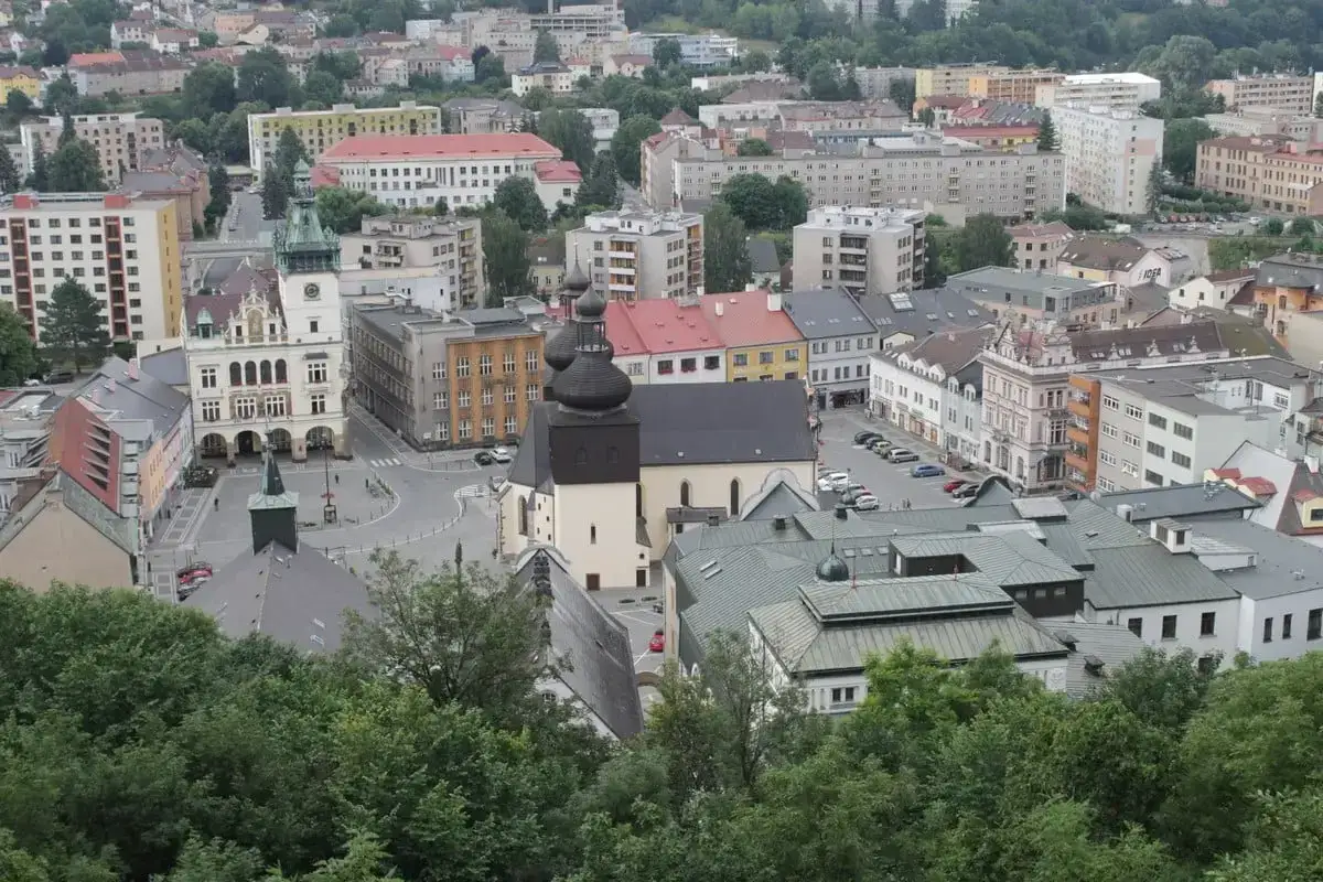 Widok na miasto z wieżą ratuszową i kościołem, zalesione wzg&oacute;rza w tle. To urokliwy zakątek Czech, gdzie nachod Czechy zaprasza do odkrywania historii.