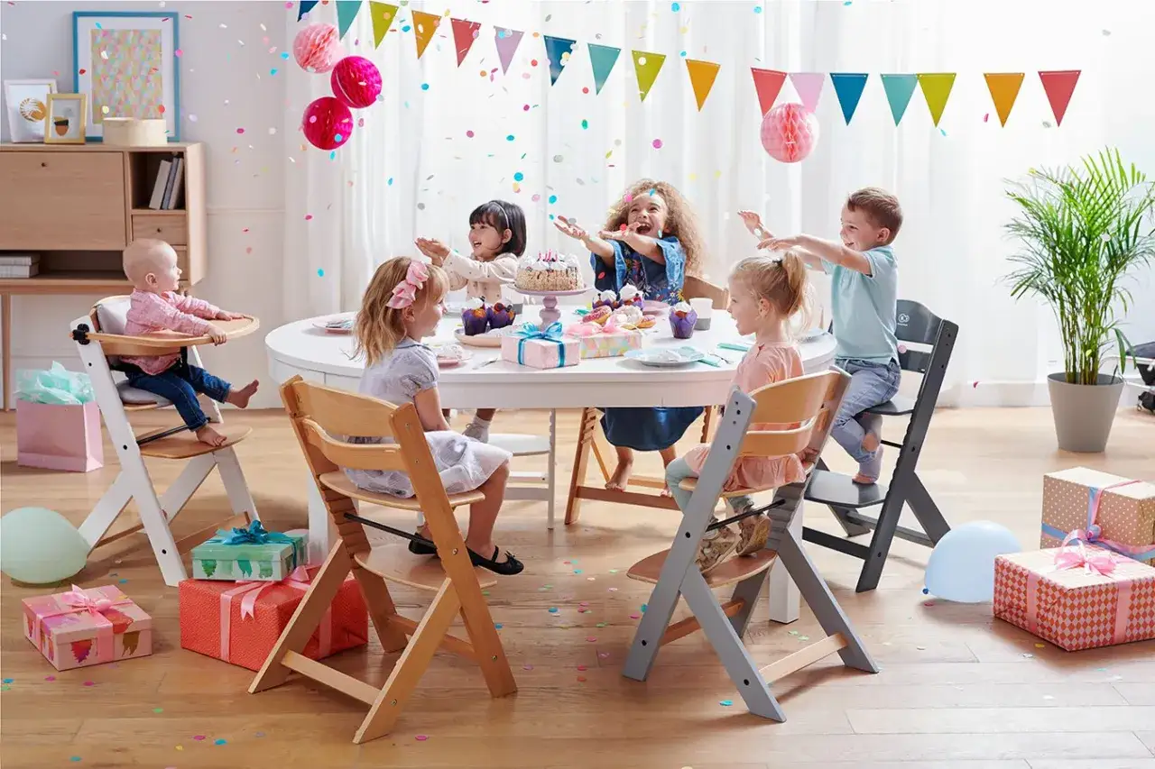 Ein Baby sitzt im Hochstuhl, bereit f&uuml;r die Party. Ab wann sitzen Babys im Hochstuhl? Sobald sie stabil sitzen k&ouml;nnen, meist ab dem 6. Monat.