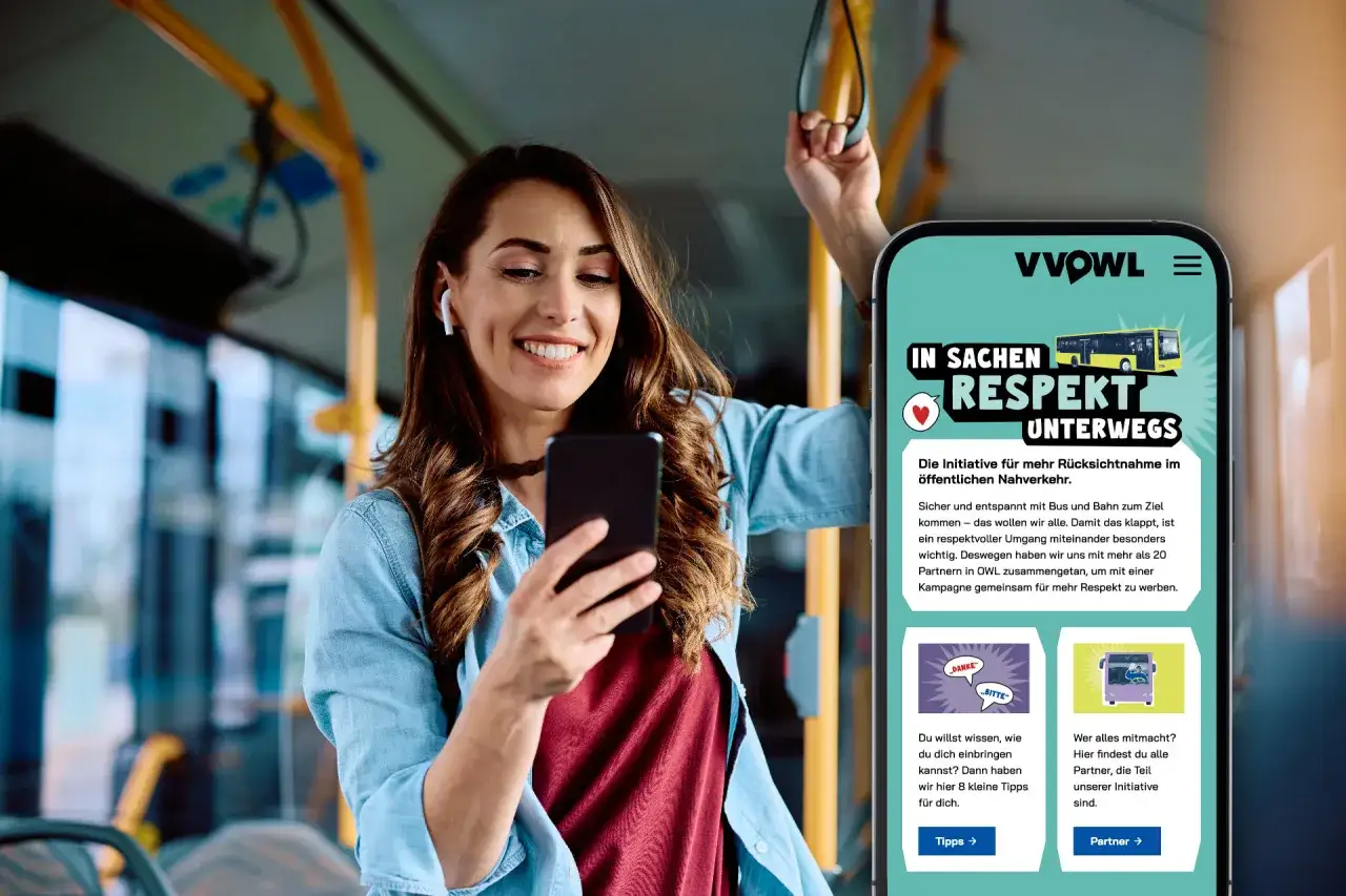 Frau im Bus schaut lächelnd auf ihr Handy, das die Kampagne