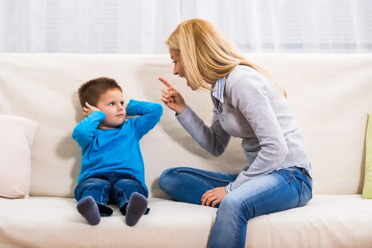Mutter schimpft mit ihrem Sohn, der die Ohren zuh&auml;lt. Der Sohn wirkt aggressiv gegen seine Mutter.