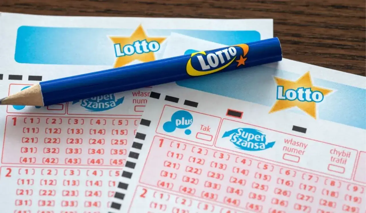 Niebieski ołówek leży na kuponach lotto z polami do zaznaczenia liczb.