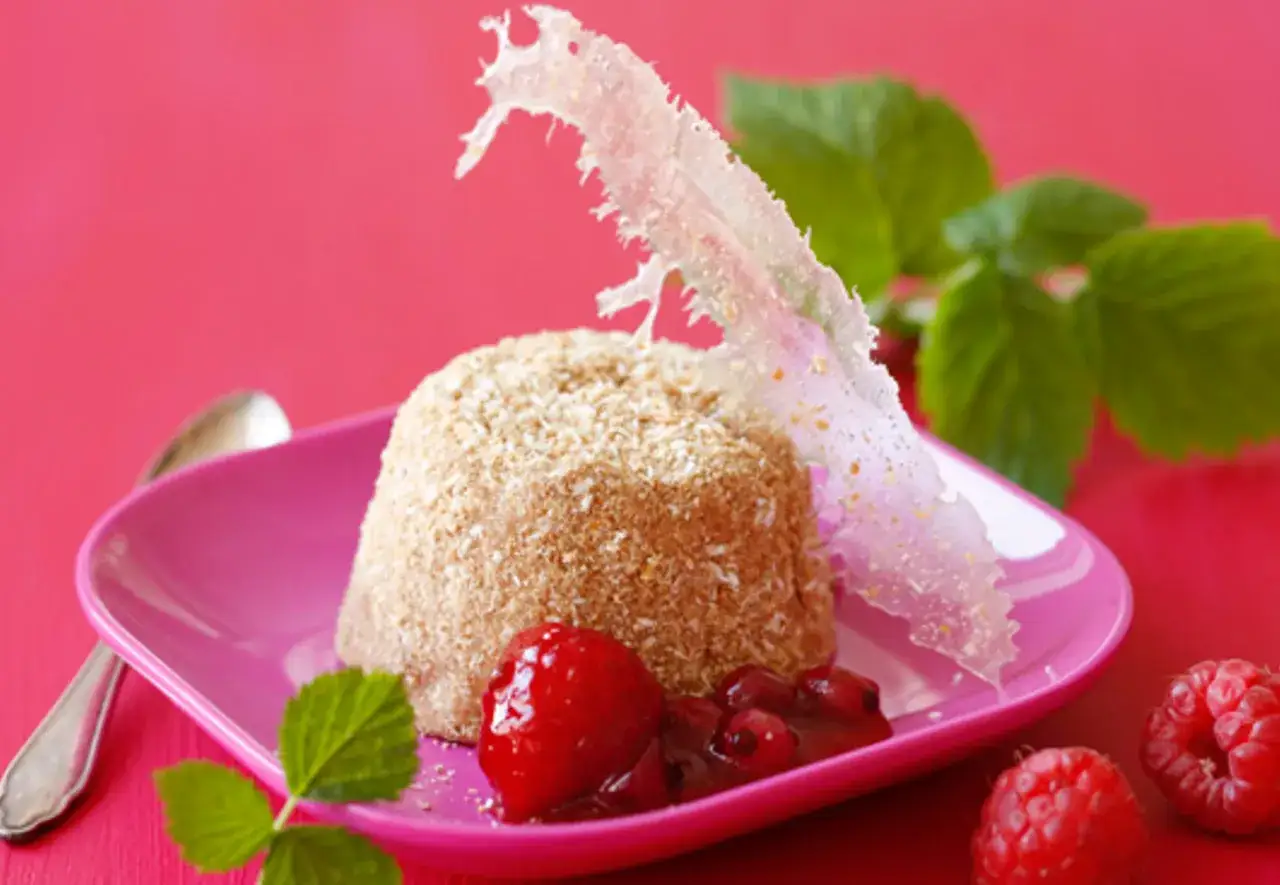 Ein köstliches Eisparfait-Rezept: Ein mit Kokosraspeln überzogener Kuchen mit Erdbeeren und Himbeeren auf pinker Platte.