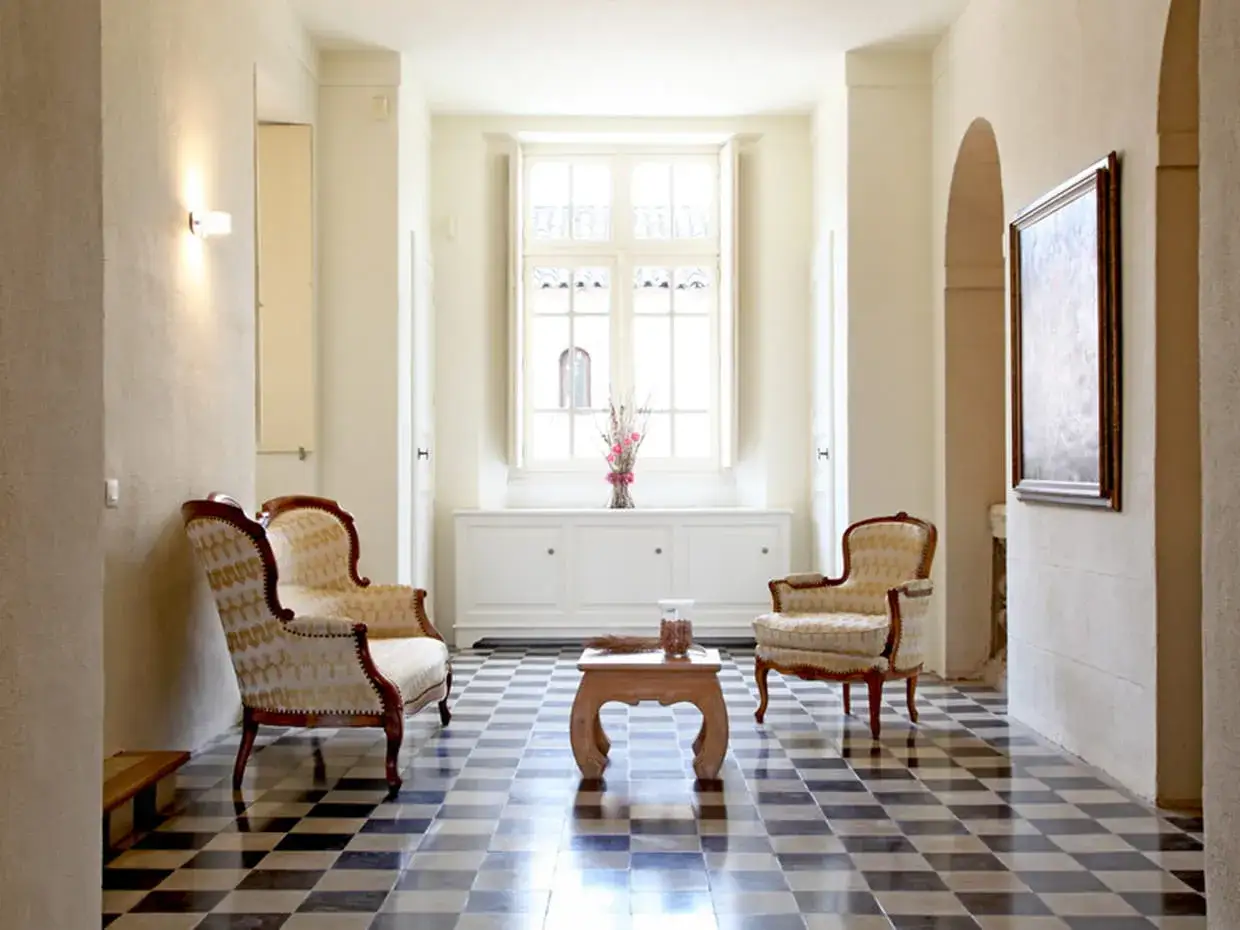 Un salon élégant où le style Louis-Philippe rencontre le contemporain. Deux fauteuils ornés sont disposés autour d'une table basse en bois.