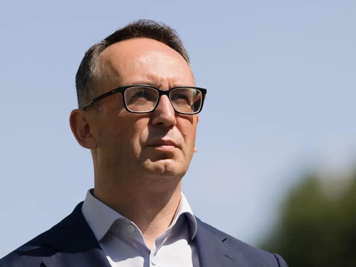 Minister infrastruktury w okularach, w garniturze, patrzy w górę.