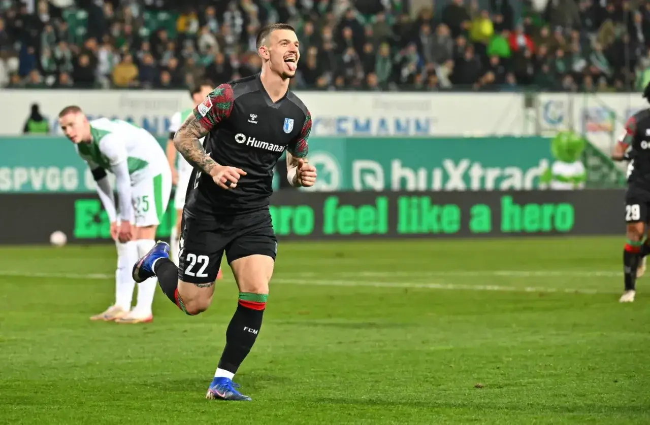Piłkarz w czarnej koszulce z numerem 22, jeden z zawodników 2. Bundesligi, cieszy się po zdobyciu bramki.
