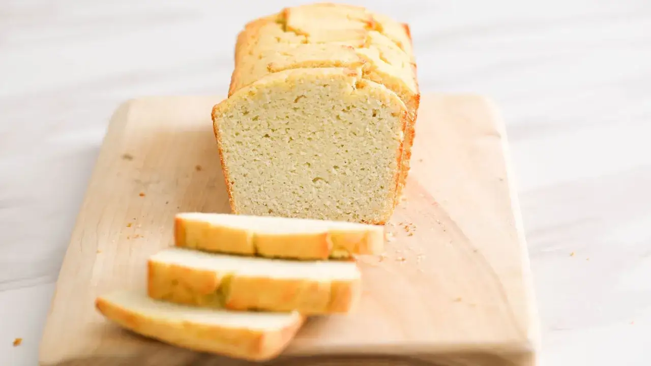 Keto chleb z mąki migdałowej i kokosowej, pokrojony na kromki, leży na drewnianej desce.