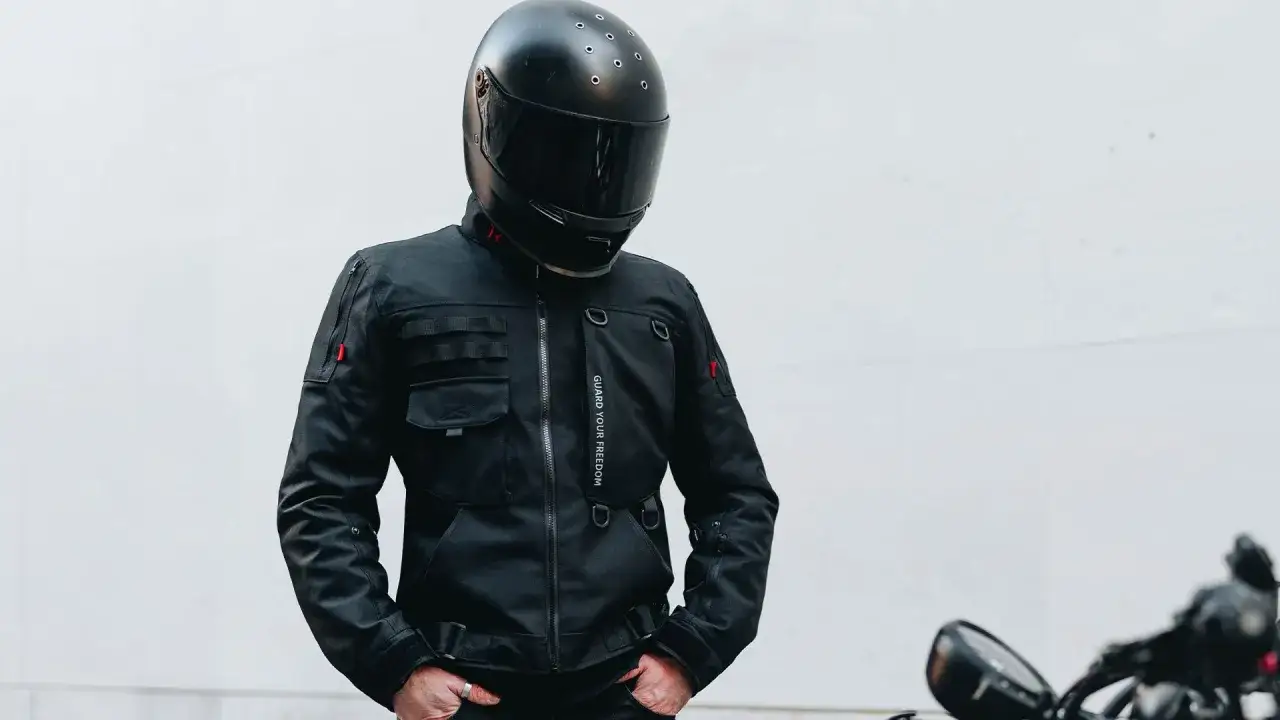 Hombre con casco negro y chaqueta de motorista, un ejemplo de los tipos de chaqueta que protegen tu libertad.