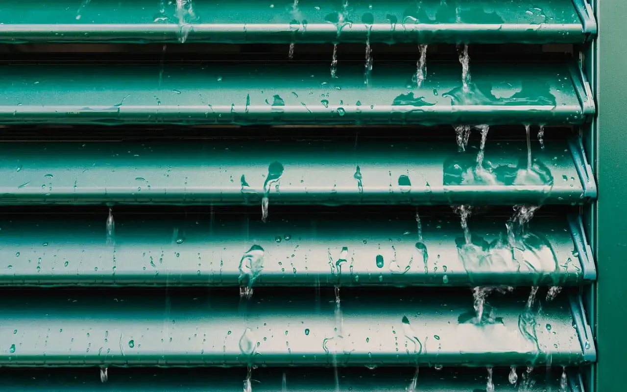 Acqua che scorre su persiane verdi, un modo efficace per capire come pulire le persiane e rimuovere lo sporco.
