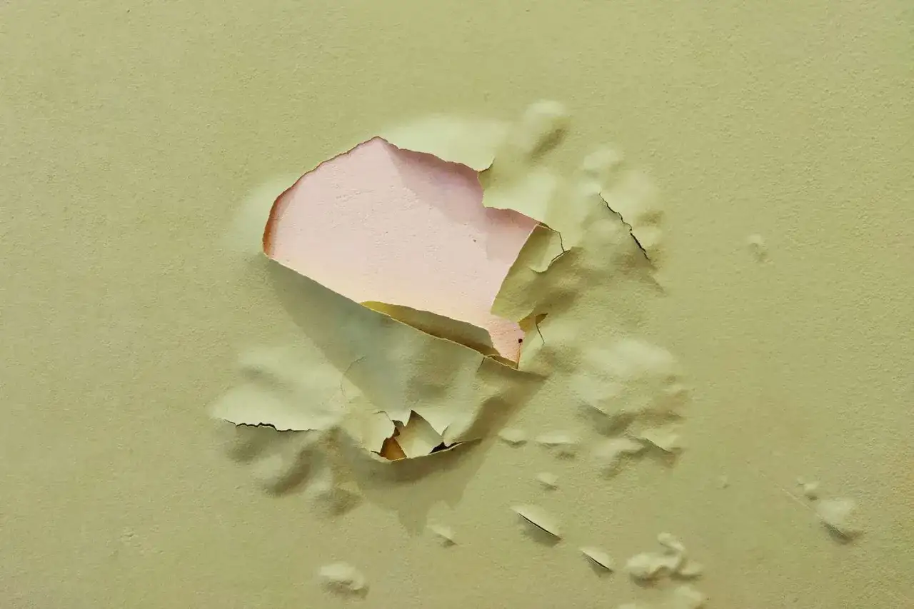 La pintura no agarra en la pared, se desprende en grandes trozos revelando una capa inferior rosada.