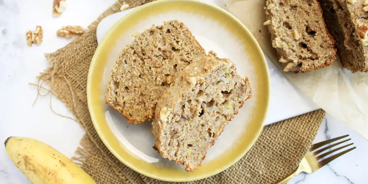 Zwei Scheiben Bananenbrot mit Nüssen auf einem gelben Teller, ein Beweis für ein köstliches Bananenbrot Rezept ohne Zucker.