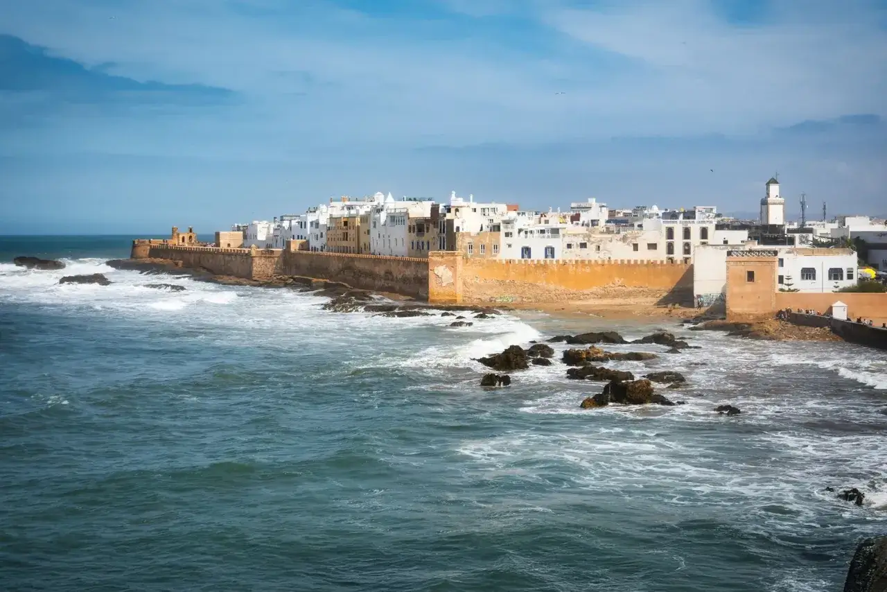 Vue de la c&ocirc;te d'Essaouira, avec ses remparts ocres et ses maisons blanches. La mer agit&eacute;e et les rochers invitent &agrave; toutes les activit&eacute;s nautiques.