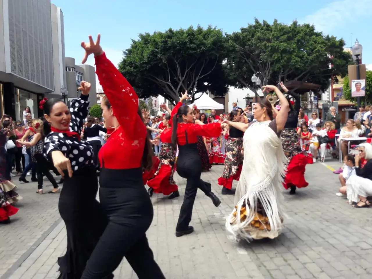 Mujeres bailan flamenco en la calle, evocando el origen de las sevillanas.