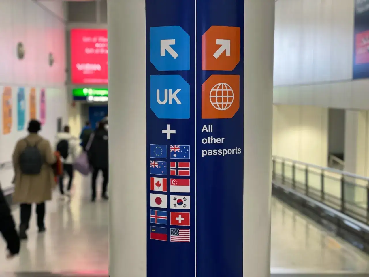 Znak informuje, czy do Szkocji potrzebny jest paszport. Wskazuje ścieżki dla paszportów UK i innych krajów, z flagami UE, Kanady, Australii i innych.