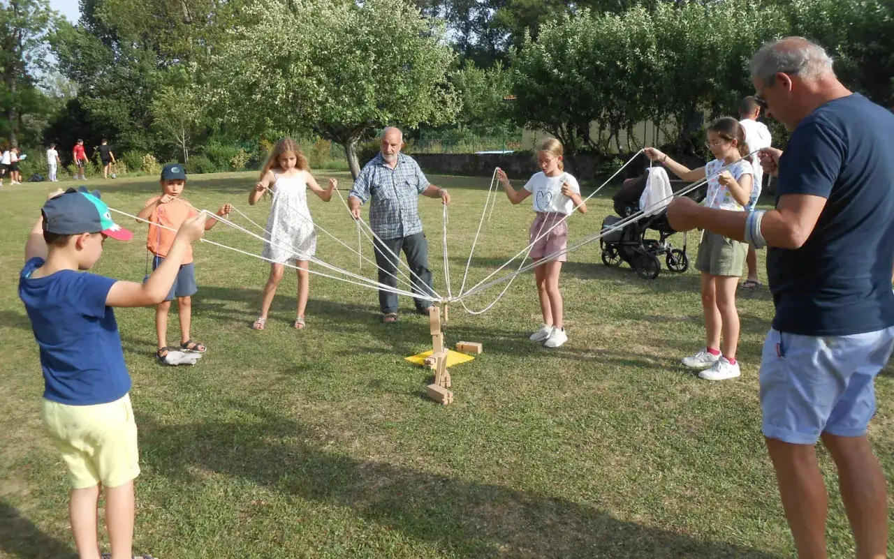 Des enfants et des adultes jouent à un jeu de corde lors d'une kermesse. 60 idées de jeux pour kermesse, une activité amusante en plein air.