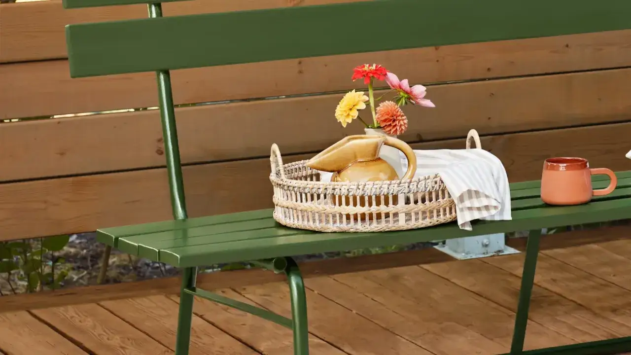 Gr&ouml;n b&auml;nk med korg, blommor och mugg. Perfekt f&ouml;r att njuta av sommaren efter att ha f&aring;tt m&aring;la trall.
