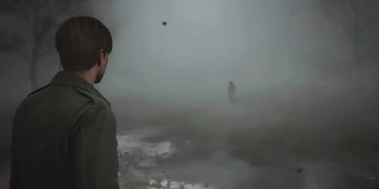 Mężczyzna w zielonej kurtce patrzy w gęstą mgłę, gdzie majaczy postać. Klimat jak z silent hill remake.