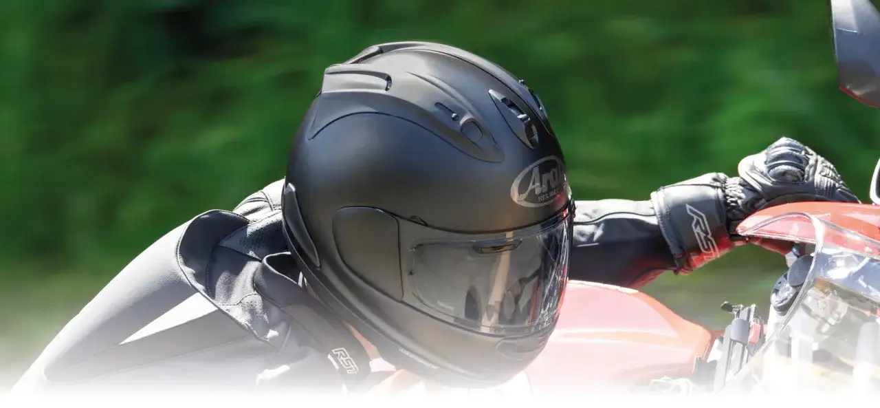 Czarny matowy kask Arai na głowie motocyklisty, gotowego do jazdy.