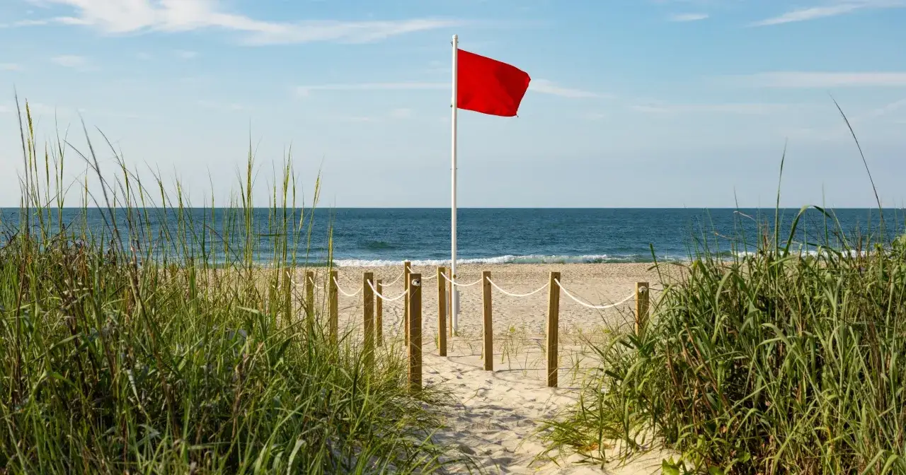 Czerwona flaga na plaży ostrzega: czy można się kąpać w Bałtyku? Woda spokojna, ale lepiej sprawdzić regulamin.