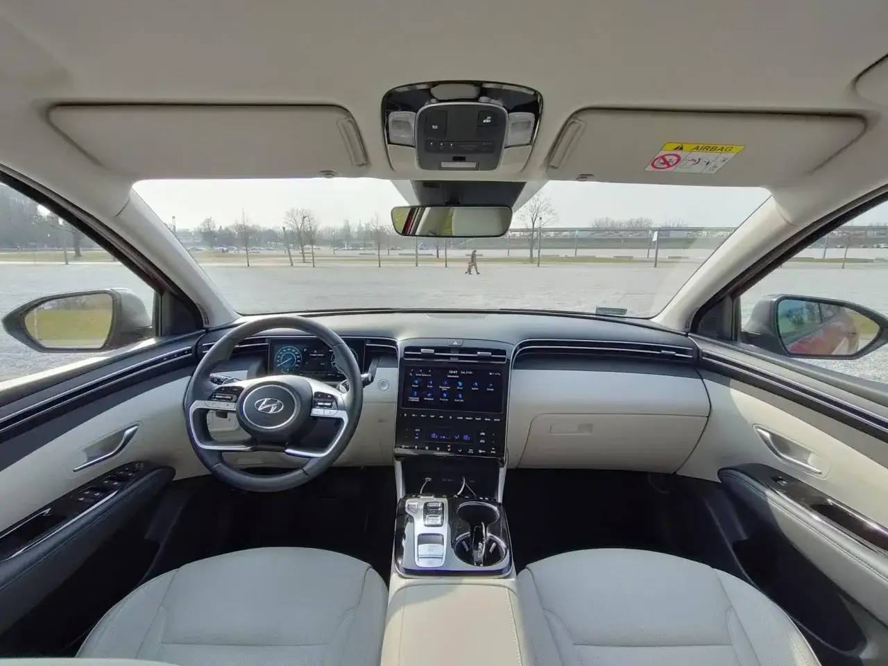 Wnętrze Hyundai Tucson Hybrid z jasną tapicerką, nowoczesnym panelem i ekranem multimedialnym.